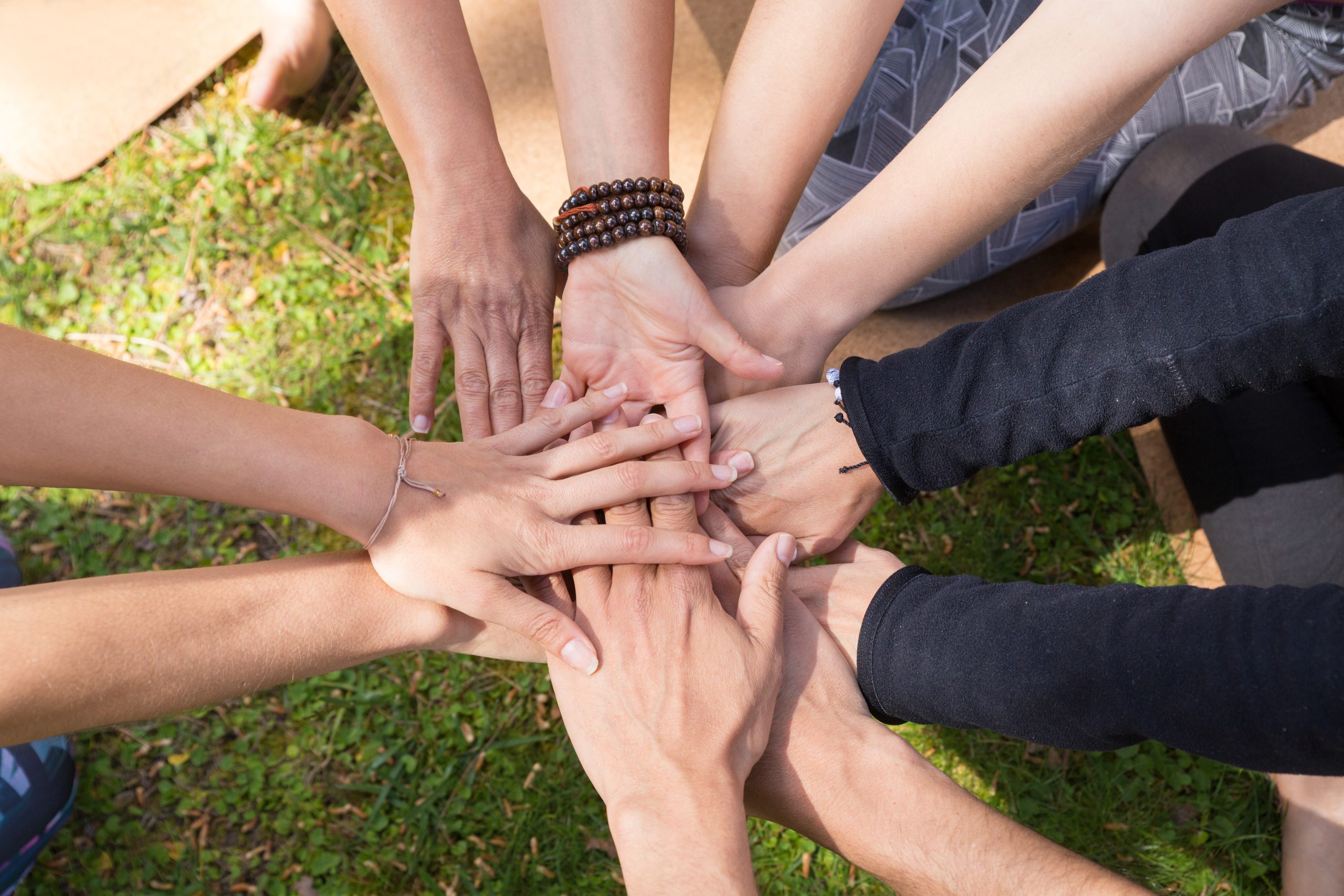 top view stack hands against green grass